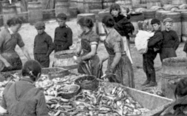 Children watch their mothers gutting herring